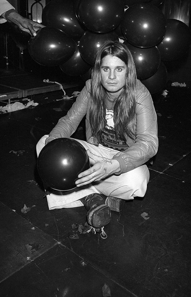 Foto a Ozzy Osbourne seduto a terra in una pista da bowling, con una palla da bowling in braccio
