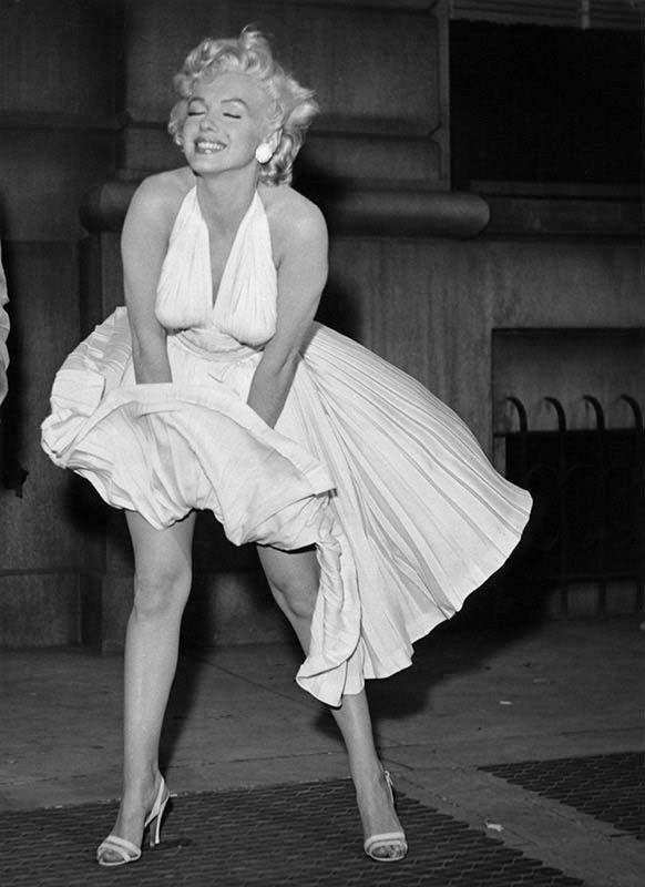 Foto a figura intera a Marilyn Monroe sopra una grata mentre l'abito svolazza per via del vento che viene dalla grata della metropolitana. Era sul set di "Quando la moglie è in vacanza".