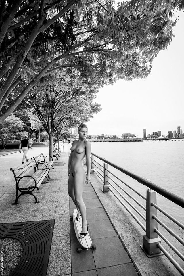 Marisa Papen nuda che fa skate su un lungomare, o meglio, lungo fiume, sotto degli alberi.