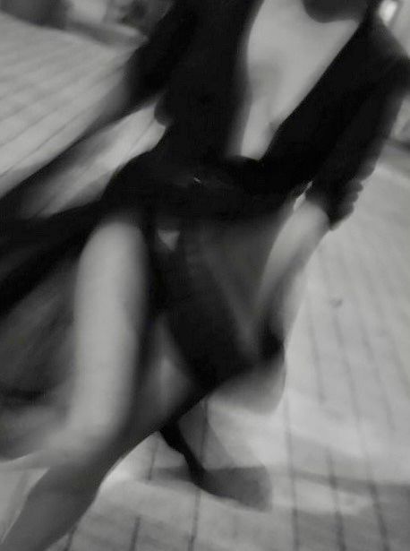 Foto sfocata al corpo di una donna in abito da sera molto succinto che cammina in strada