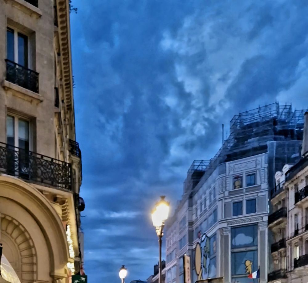 Ciel de crépuscule Rue de Rivoli à Paris cet automne, tout bleu nuit, irrigué de nuages blancs, sur lesquels ressortent les lueurs des réverbères