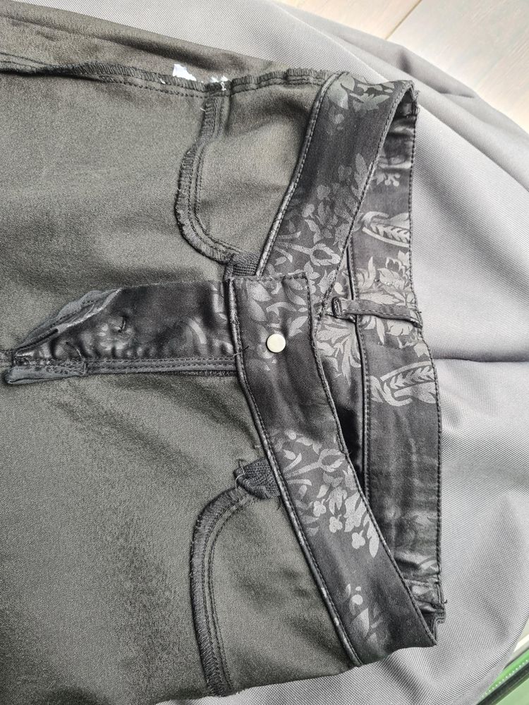 Sideways view of the top part of black-flowery pants turned inside out. Where there should be pockets, there's just a seam. There's even a little bit of extra fabric that's sewn into the belt to reinforce or hang the pocket weight off of.