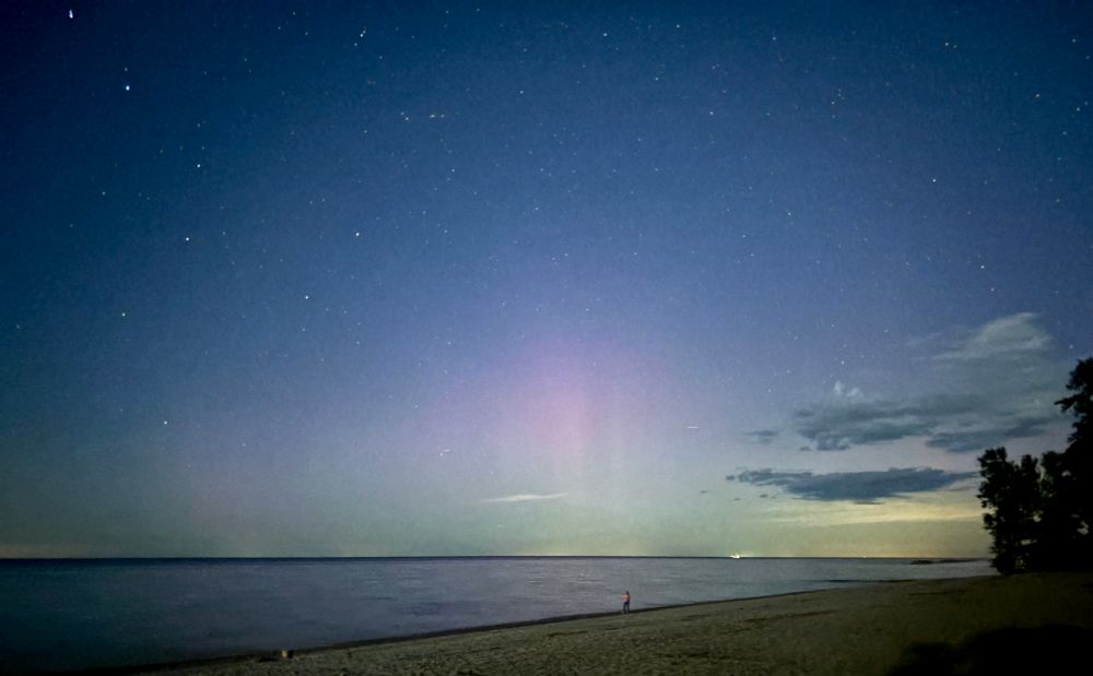 Photo of some faint pink aurora pillars over Lake Erie. 