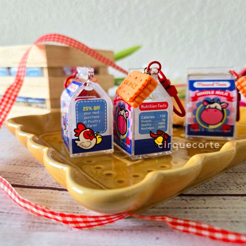 A photo of my Harvest Moon themed milk carton charms! This is showing the designs on the sides. One has a chicken and a baby chick, and the other side has a cowbell.

Text on the charms: "25% Off your next purchase at Poultry Farm!"

"Nutrition Facts
Calories: 150
Protein: 8g
Quality: 100%
Nostalgia: 200%"