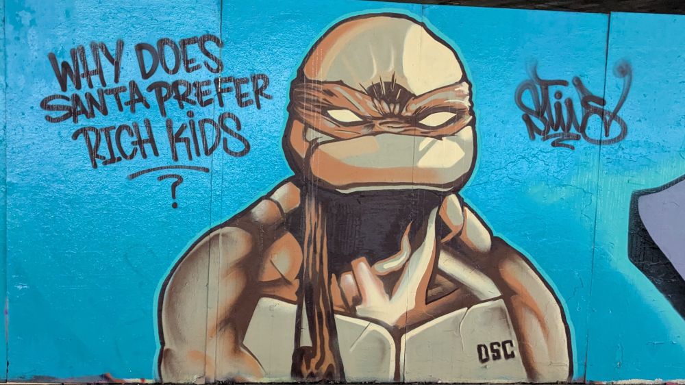 Street art ninja turtle asks why santa prefers rich kids.