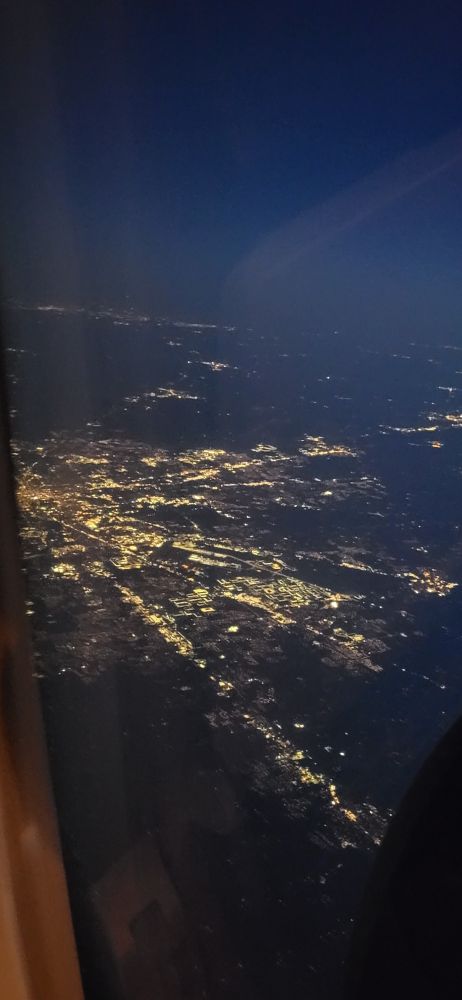 Indianapolis at night from overhead in a plane. The buildings are lit up, showing the city layout.