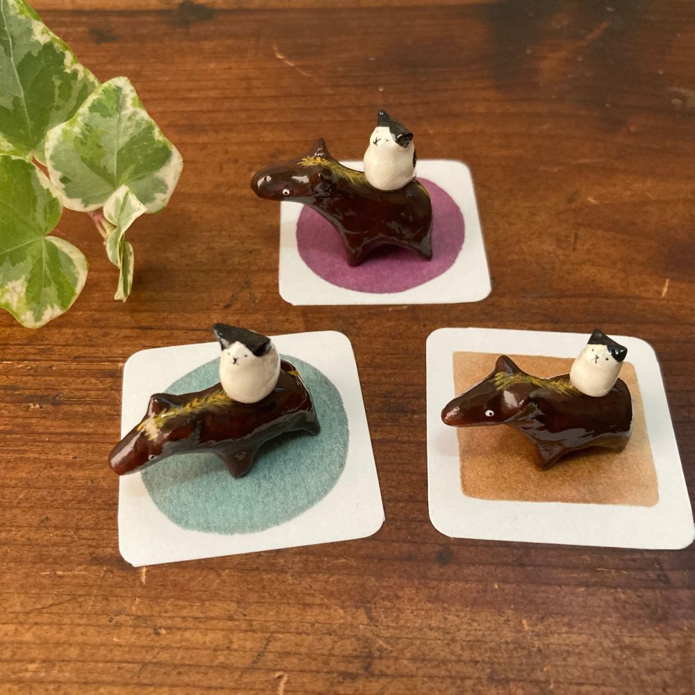 背中にチビ白黒猫を乗せた、濃茶色のつやつや豆馬3頭。樹脂粘土製、台紙付き。