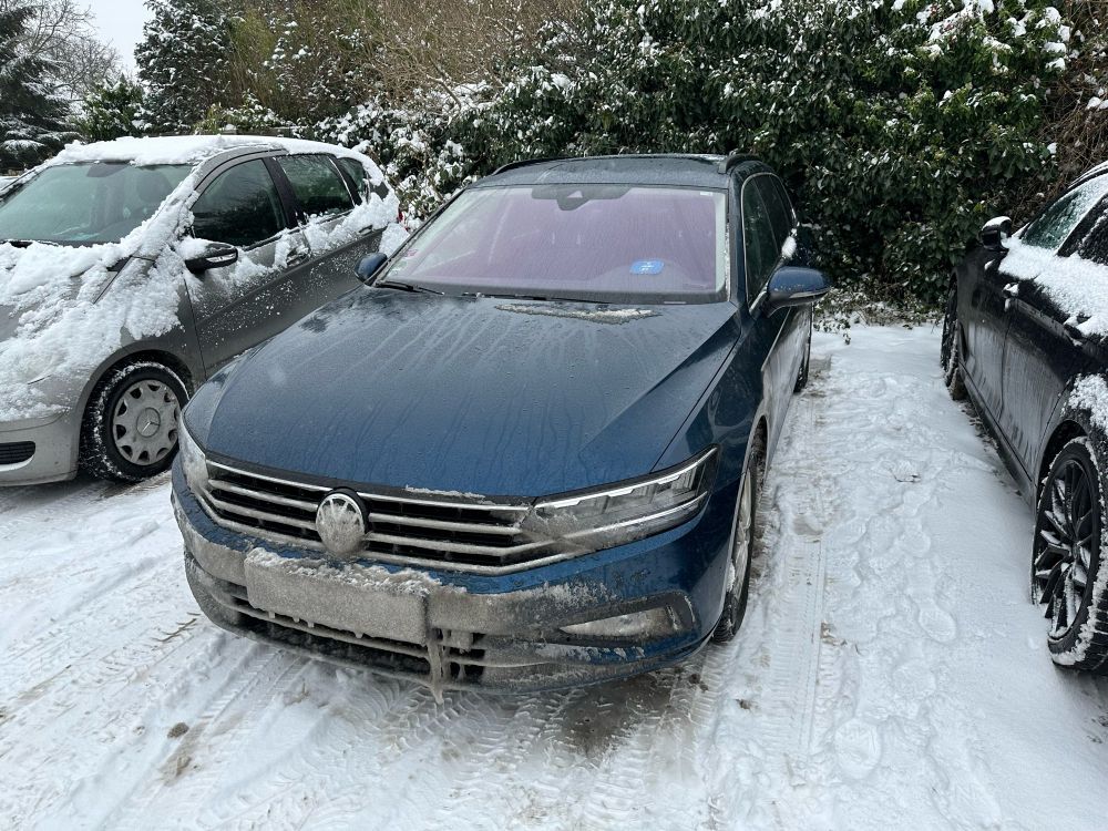 Ein Auto mit durch Schnee unlesbarem Nummernschild vorne.