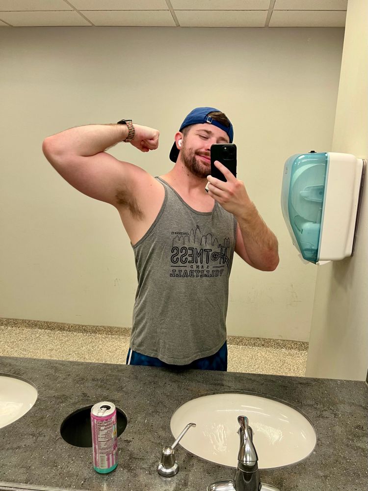 man flexing in a gray tank
