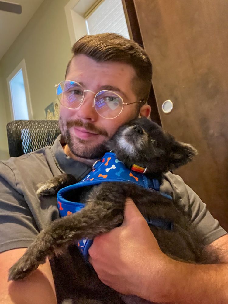 man with glasses and a black pomeranian 