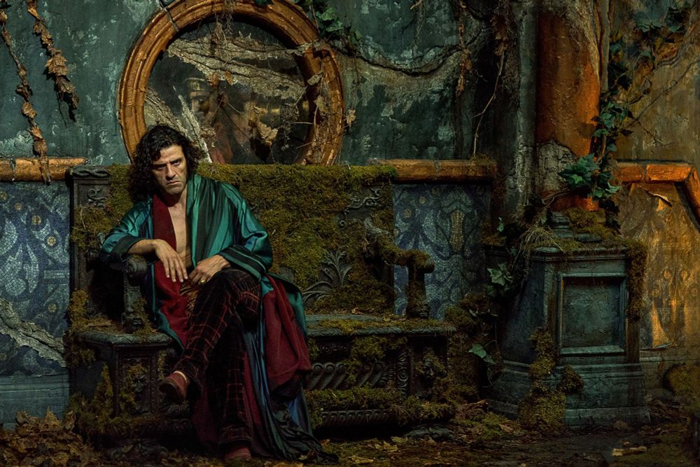 Oscar Isaac as Victor Frankenstein. Assis sur un banc de bois couvert de mousse dans un palais lui-même décati et couvert de lianes, de vignes, etc