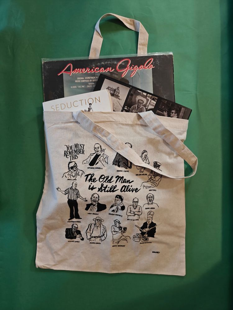 A tote bag featuring drawings of directors and the text You Must Remember This and The Old Man is Still Alive. The tote fits an LP, a softcover and hardcover book
