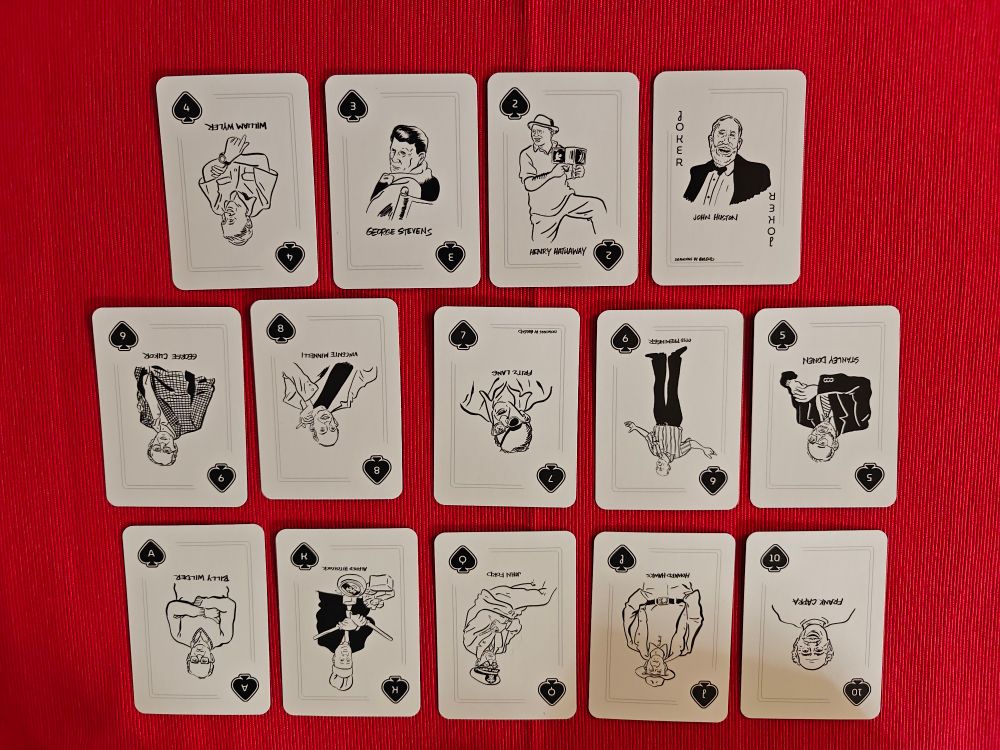 A full suit of playing cards on a red background. The cards feature a drawing of a different director on each card. 