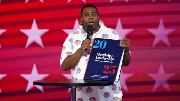 Kenan Thompson holding a book of Project 2025.