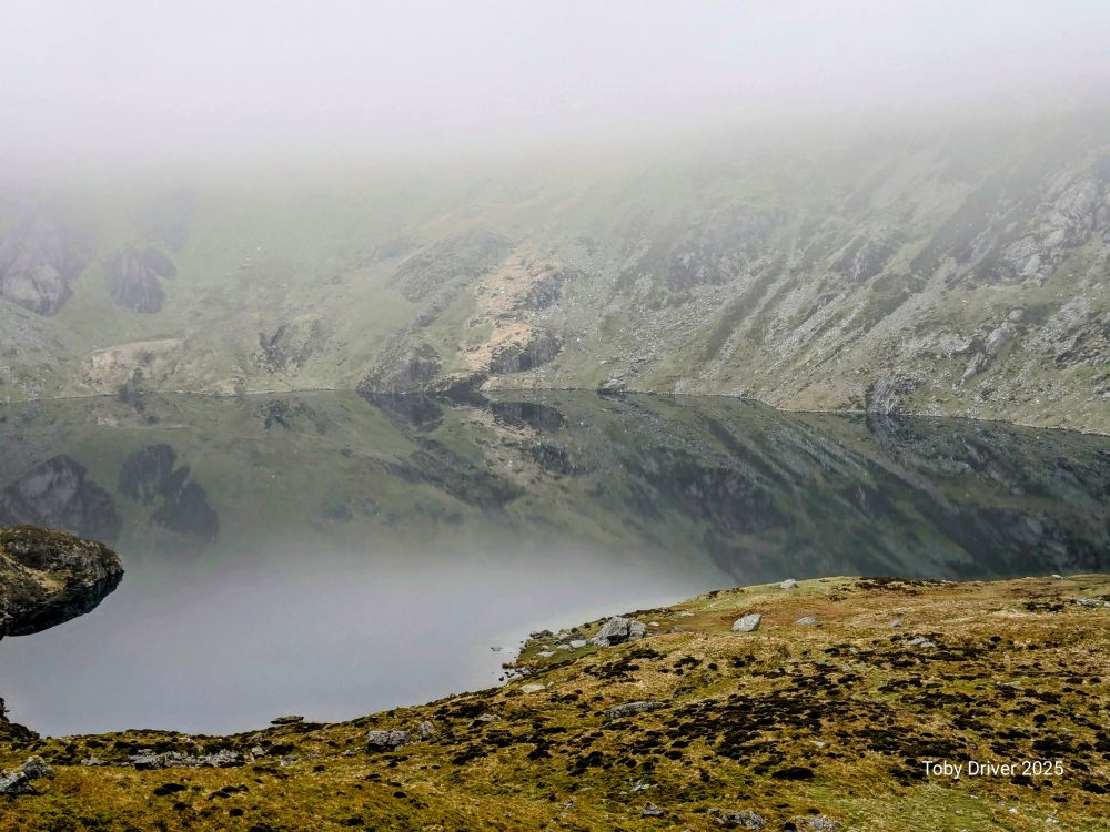 A mirror surface on a mountain lake in the mist