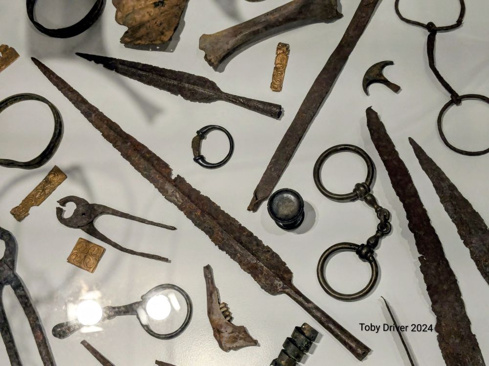 An array of iron and bronze finds in a white museum case