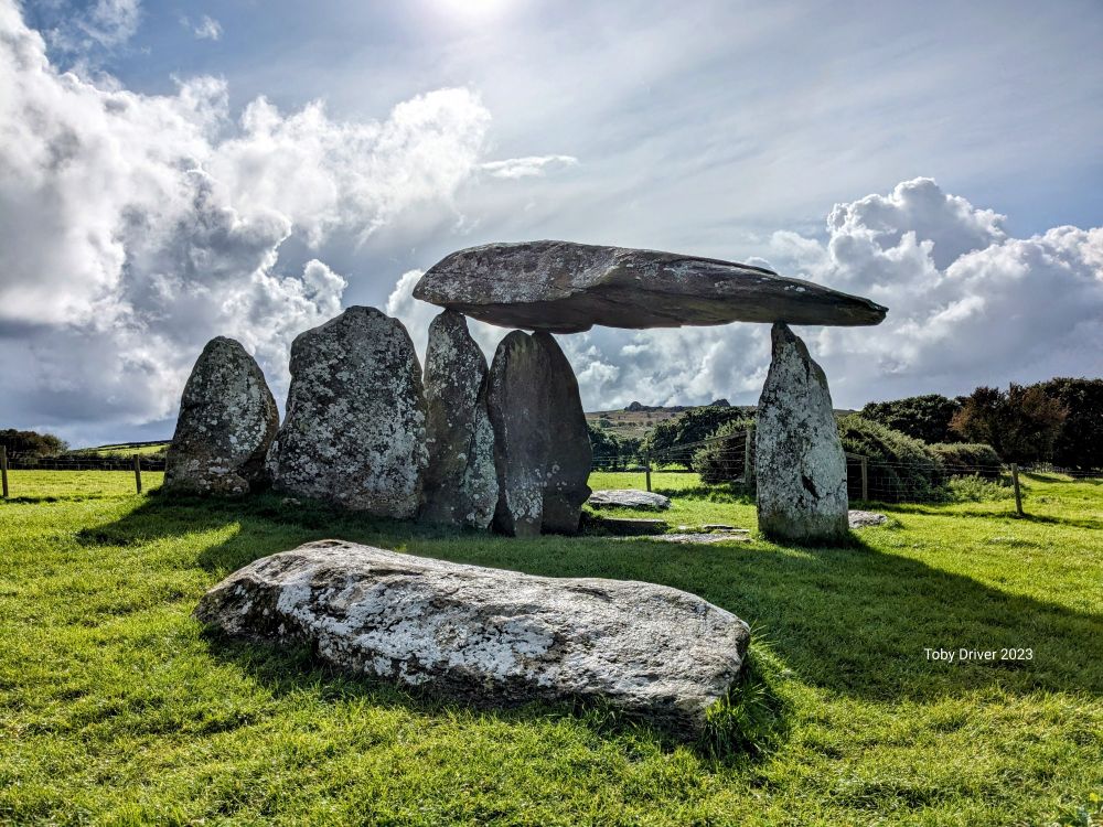 A stone chamber tomb with a stormy sky beyond 