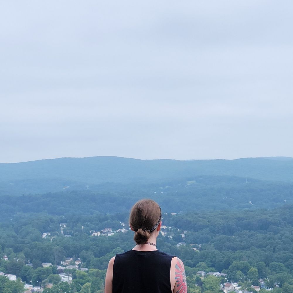 sheisinfinite looking out at the horizon on a mountaintop.