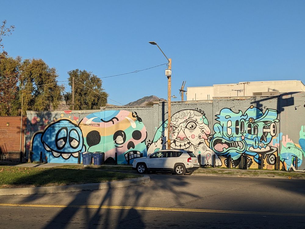 A mural of 4 heads in different styles by Chuck Landvatter.
