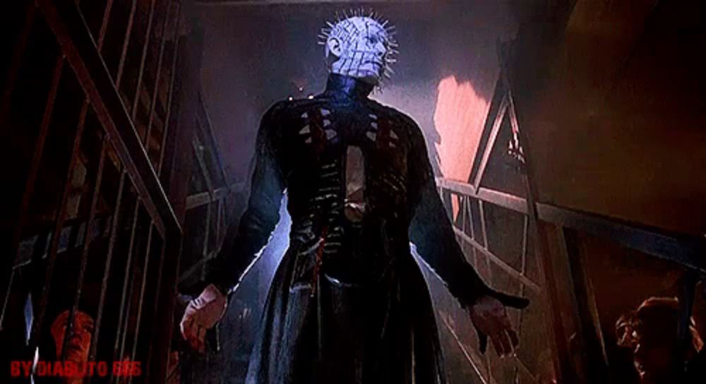 a man with a very spiky head is standing in a dark room holding a knife .