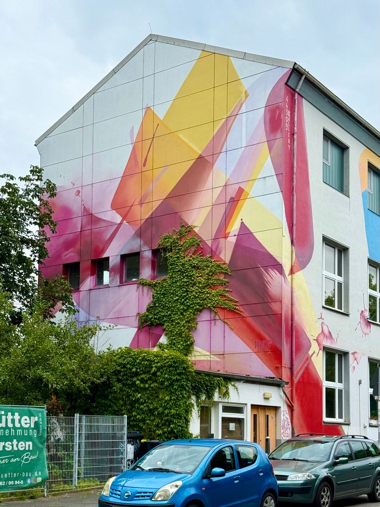 A white, dark red, yellow mural by street artist MadC in Dortmund.