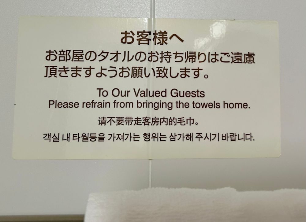Wall sign above towel rack in hotel room bathroom in Japan that says in Japanese, English, Chinese, and Korean:
“To Our Valued Guests
Please refrain from bringing the towels home.”