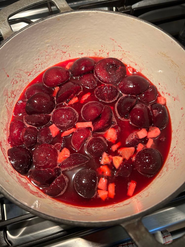 Plum and lemon pieces cooking in a pot.