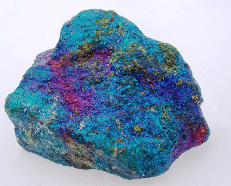 Bornite rock sample on white background showing deep turquoise and magenta colours via geologyscience.com