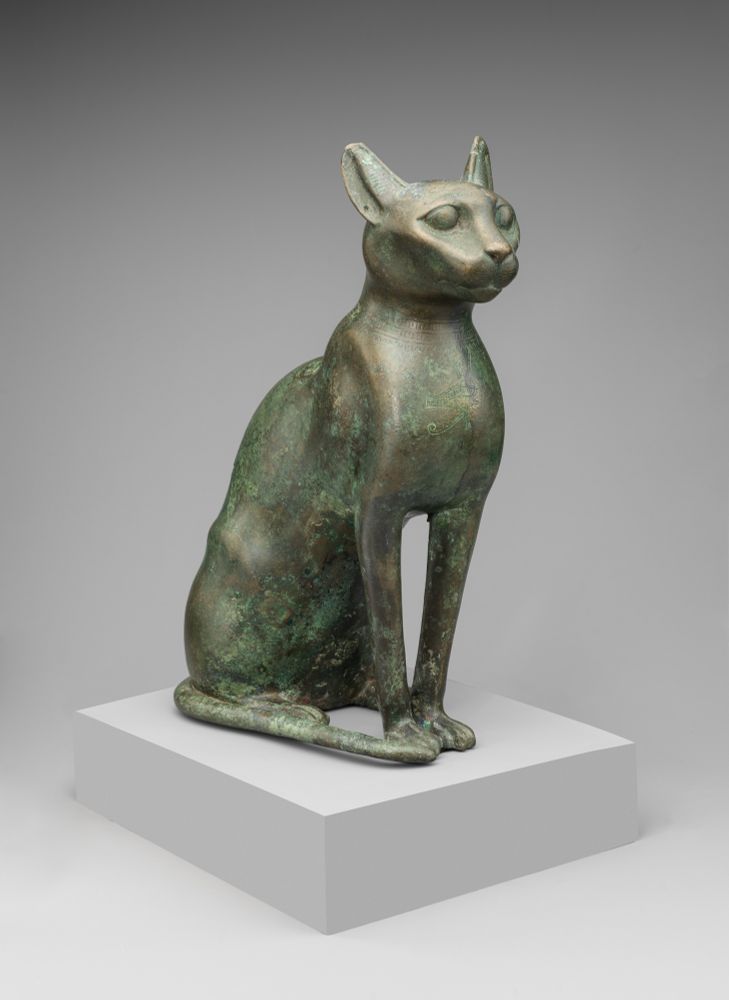 Cat Statuette intended to contain a mummified cat
Ptolemaic Period
332–30 BCE
On view at The Met Fifth Avenue in Gallery 899
“The cat was the sacred animal of the goddess Bastet, a great and benevolent Egyptian goddess. For the Egyptians, the goddesses Bastet and Sakhmet were two aspects of divine power. Sakhmet, the lioness, represented dangerous, potentially destructive forces. Bastet, the feline of the house, incorporated the benevolent aspects of a deity that could be pacified by rituals.

In Bastet's honor, mummified cats, sometimes in impressive bronze or wooden containers, were donated at her temples, of which the most important were located at Bubastis and Saqqara. The mummies were then buried within her temple precincts.

This statue was the container for a mummified cat. Clearly this is not an ordinary cat. Its pierced right ear once held a gold ring (now lost), and suspended from its incised necklace is a wedjat-eye pendant. An impression of majesty is created by the cat's erect and dignified pose and the alert expression of the eyes. The sleek muscles and long graceful legs convey a sense of controlled power.

Cats were first domesticated by the Egyptians in the Middle Kingdom for their mouse-hunting abilities. By New Kingdom times they had also become household companions. In tomb scenes they frequently appear seated beneath the chairs of their owners or on sporting boats in the Nile marshes, where they flush out birds for their masters.”

Via the Met