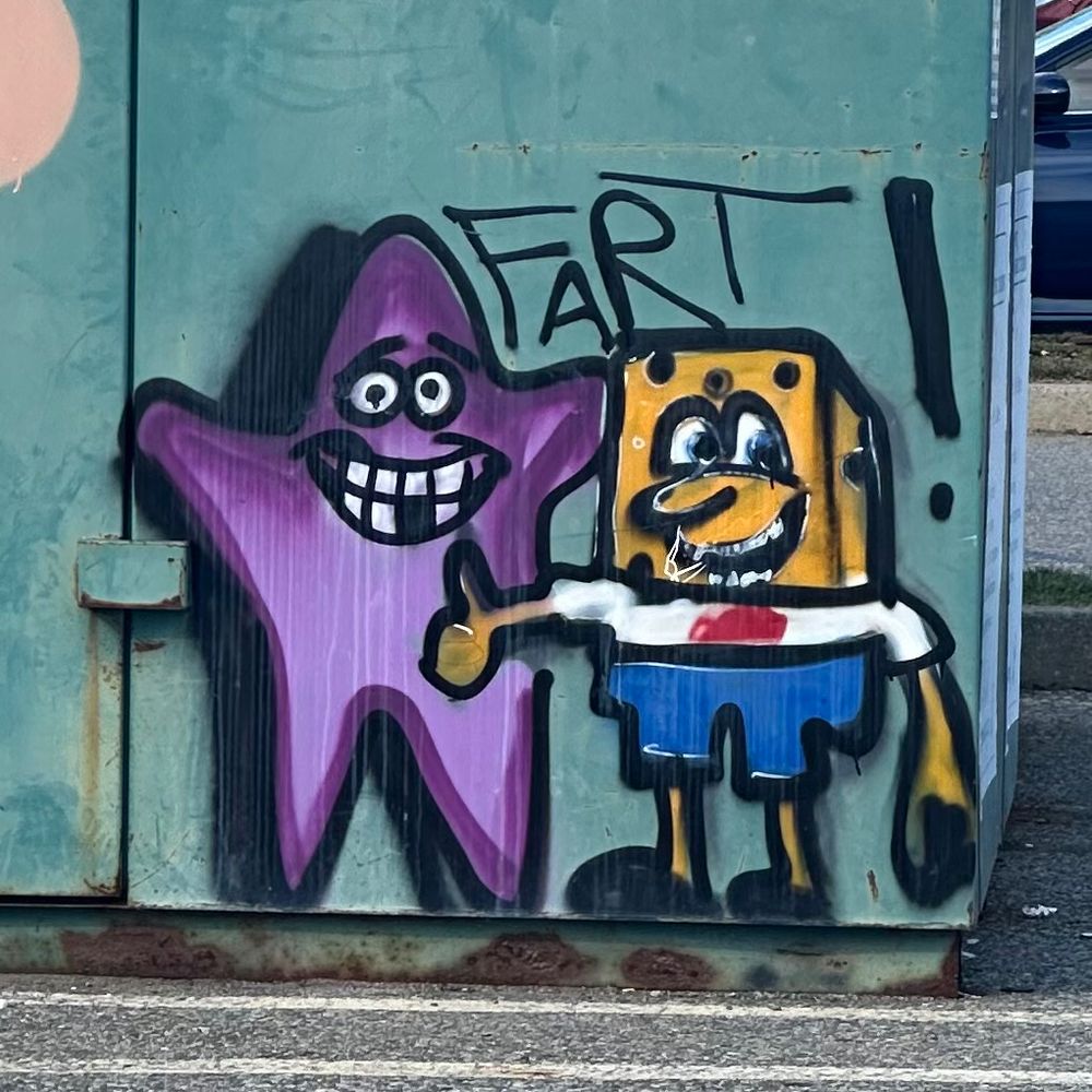 A graffiti on a dumpster of SpongeBob SquarePants giving a thumbs up and his pal Patrick waving. Above them is painted the word “Fart!”