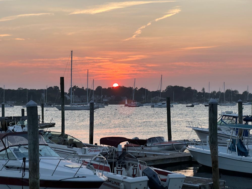 Setting sun over a small harbor. Boats and docks criss-cross in the foreground