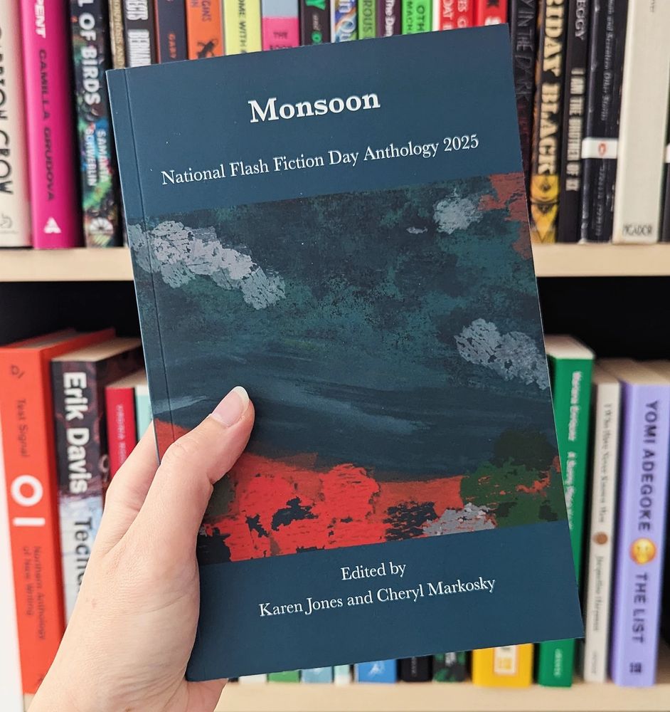 Photo of my hand holding up the National Flash Fiction Day Anthology 2025 book, titled: Monsoon.