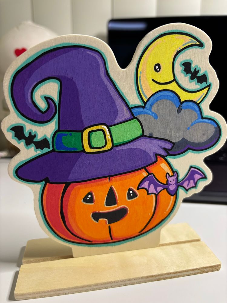 Wooden Halloween decoration of a pumpkin wearing a witch hat. 