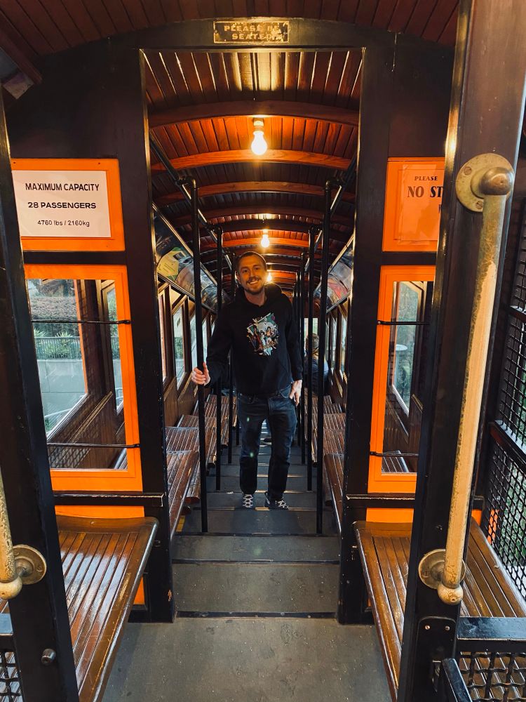 I am in the funicular car of Angels Flight, smiling and wearing a hoodie.