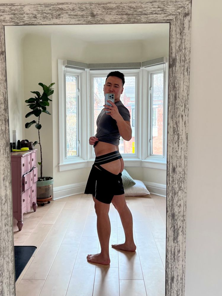 Mirror selfie of a man wearing a jockstrap pulled up to show butt