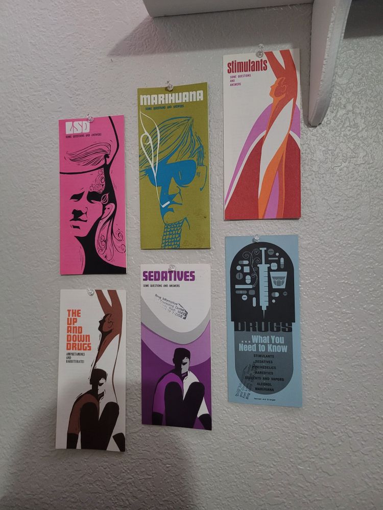 6 pamphlets tacked to a wall in stairstep patterns. all of them have colorful minimalist and flowy art design and drug-related topics