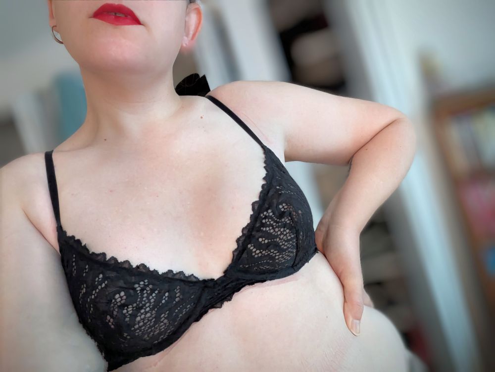 a white woman in a black lacy bra and red lipstick waiting expectantly 