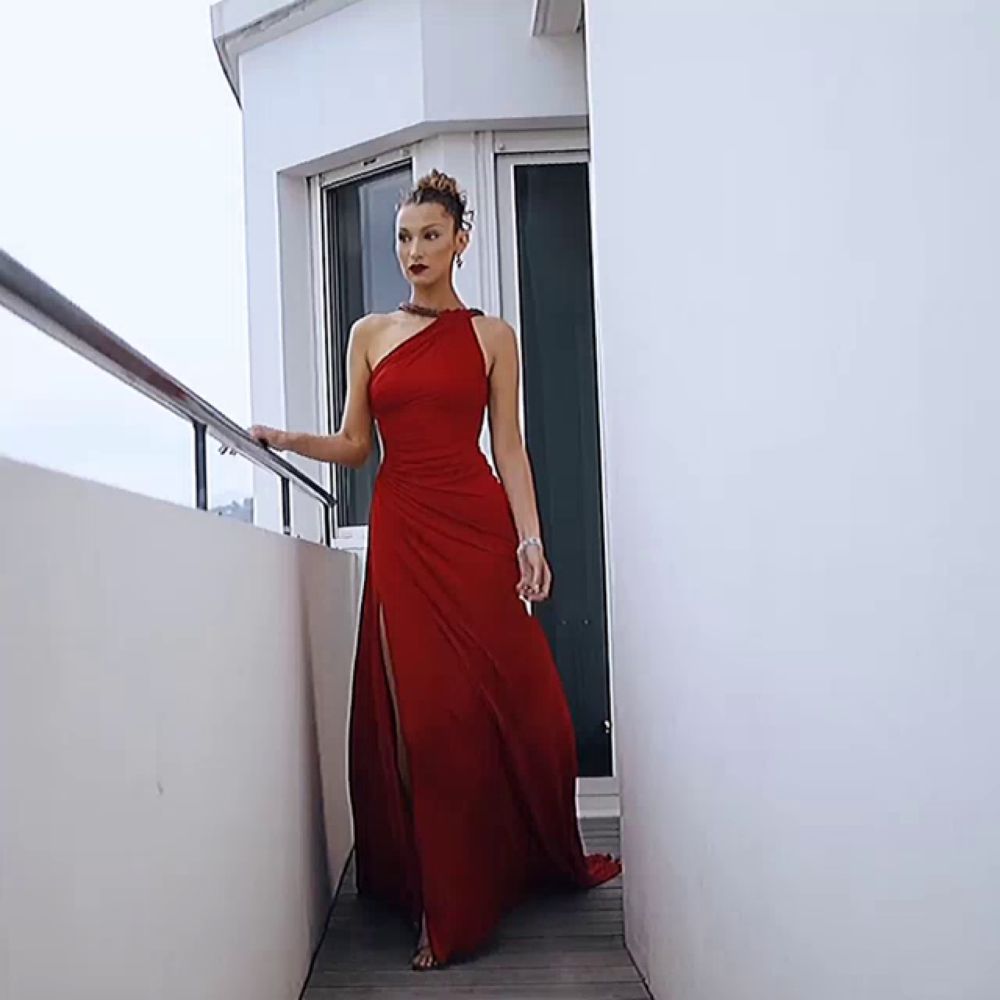 a woman in a red dress is standing next to a white wall