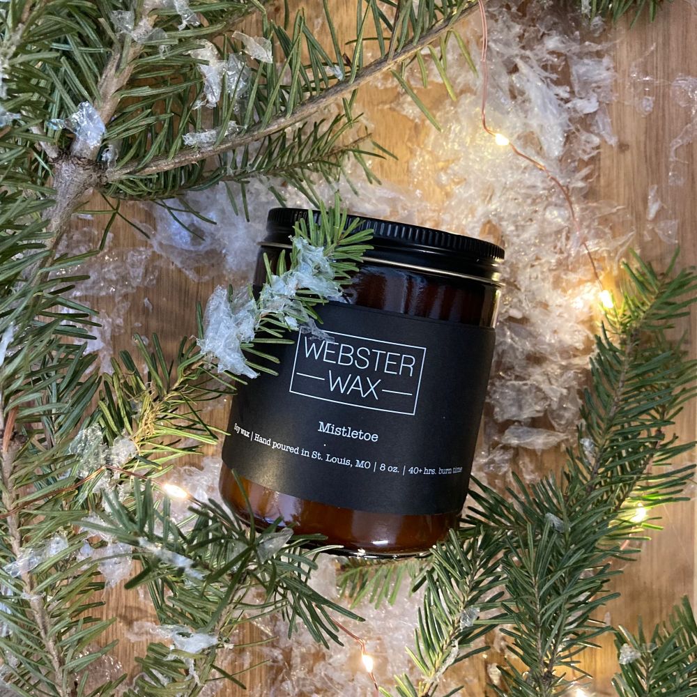 Mistletoe candle styled amongst cedar boughs and white lights. 
