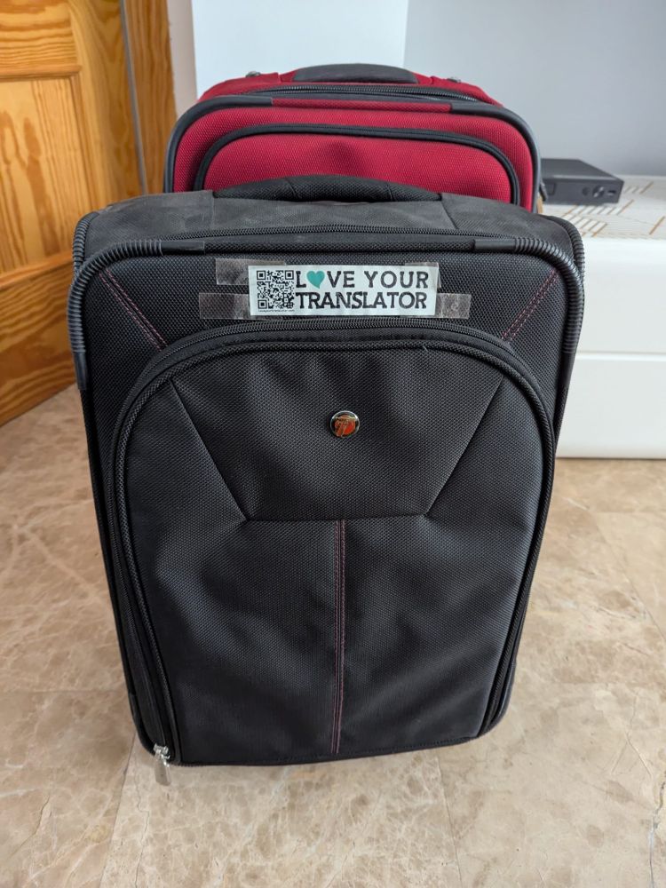 Dos maletas cerradas, una de ellas con una pegatina en la que se puede leer el eslogan Love Your Translator.