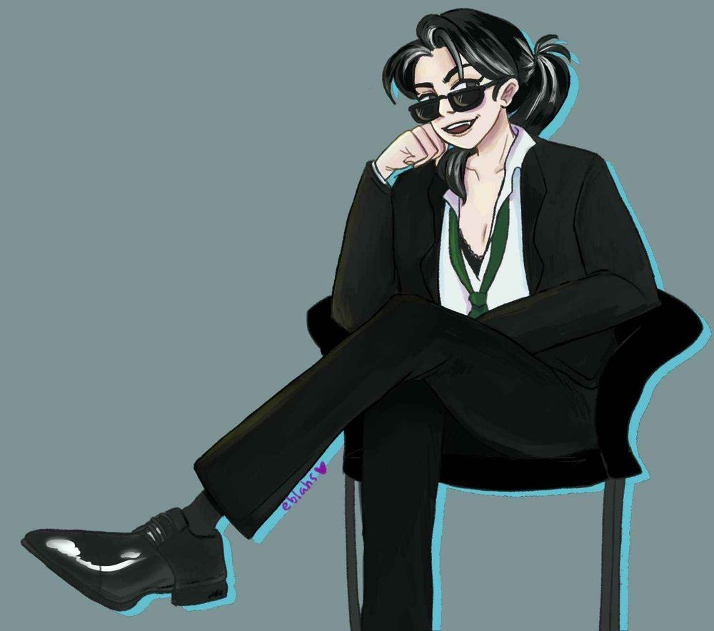 A woman in sunglasses, a black suit and green tie. The shirt is unbuttoned revealing skin underneath. She has gray and black hair and vampire fangs. She is sitting with her legs crossed.