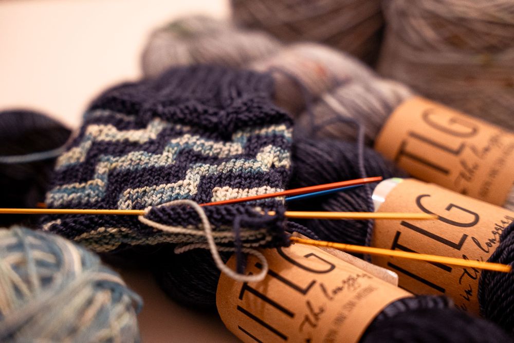 Strickzeug (Socke mit grafischem Muster) und Wolle in Blautönen