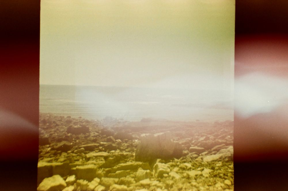 Old fujifilm photo taken by a Diana mini of a rocky shore at the beach 