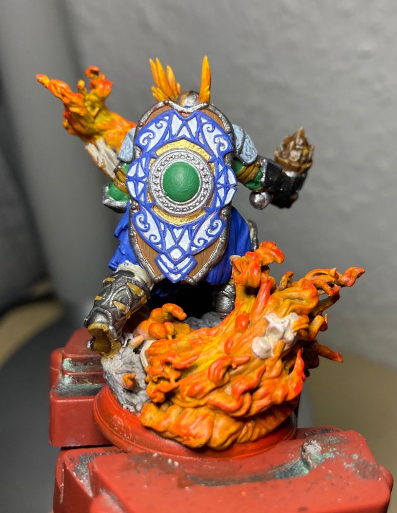 A photo of a Dungeons and Dragons miniature from the back, showing a cleric in full armor and an ornate shield on the back.