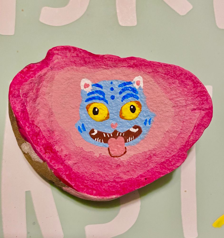 Hand painted rock with a stylized  depiction of Derpy the demon tiger from KPop Demon Hunters 