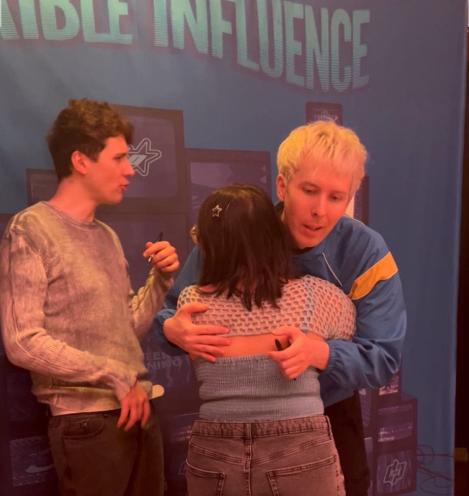 terrible influence tour meet and greet. i hug phil, holding a dvd cover in my hand, dan making an ‘oooo’ face next to us.
