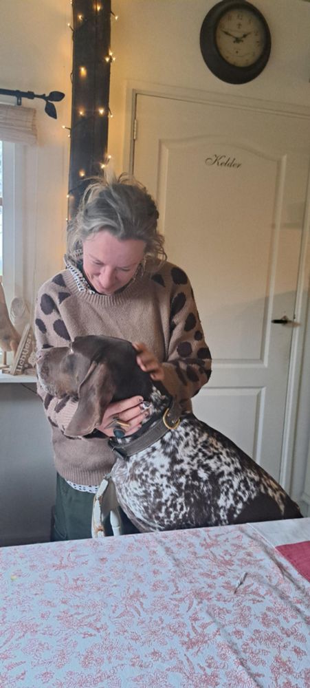 Small woman in love with a brown and white dog who's sitting at the table.