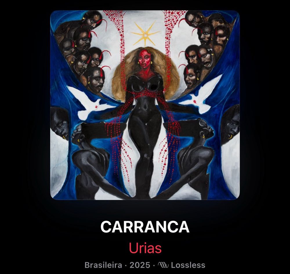 Captura de tela de um aplicativo de música com a capa do disco “Carranca” da artista Urias. Uma pintura que retrata uma mulher preta ao centro. Ela tem o rosto e parte do dorso pintados de vermelho e volumosos cabelos loiros, algo que parece uma estrela paira sobre a cabeça dela. De forma simétrica as laterais possuem uma pintura azul que emoldura a mulher e remete a água ou tecidos, rostos de homens aparecem  amontoadas ao fundo na parte superior, tem também imagens de pombas no centro da lateral e outras mulheres pretas na parte inferior. 