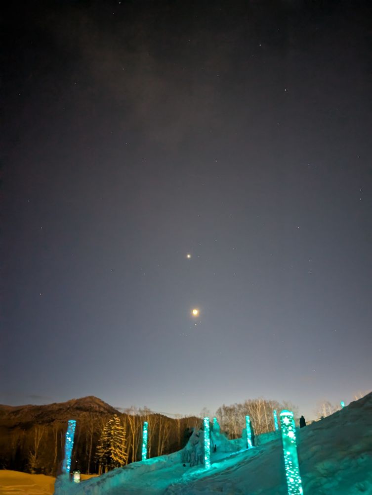 The moon and stars in alignment over a path lit by glowing posts