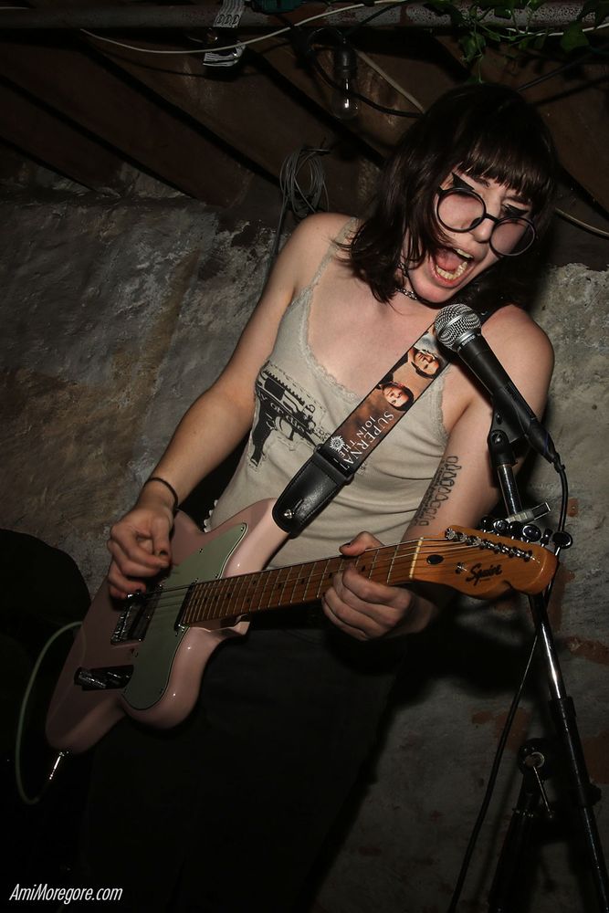 Eva from The Civil War in France playing guitar and barking into a microphone